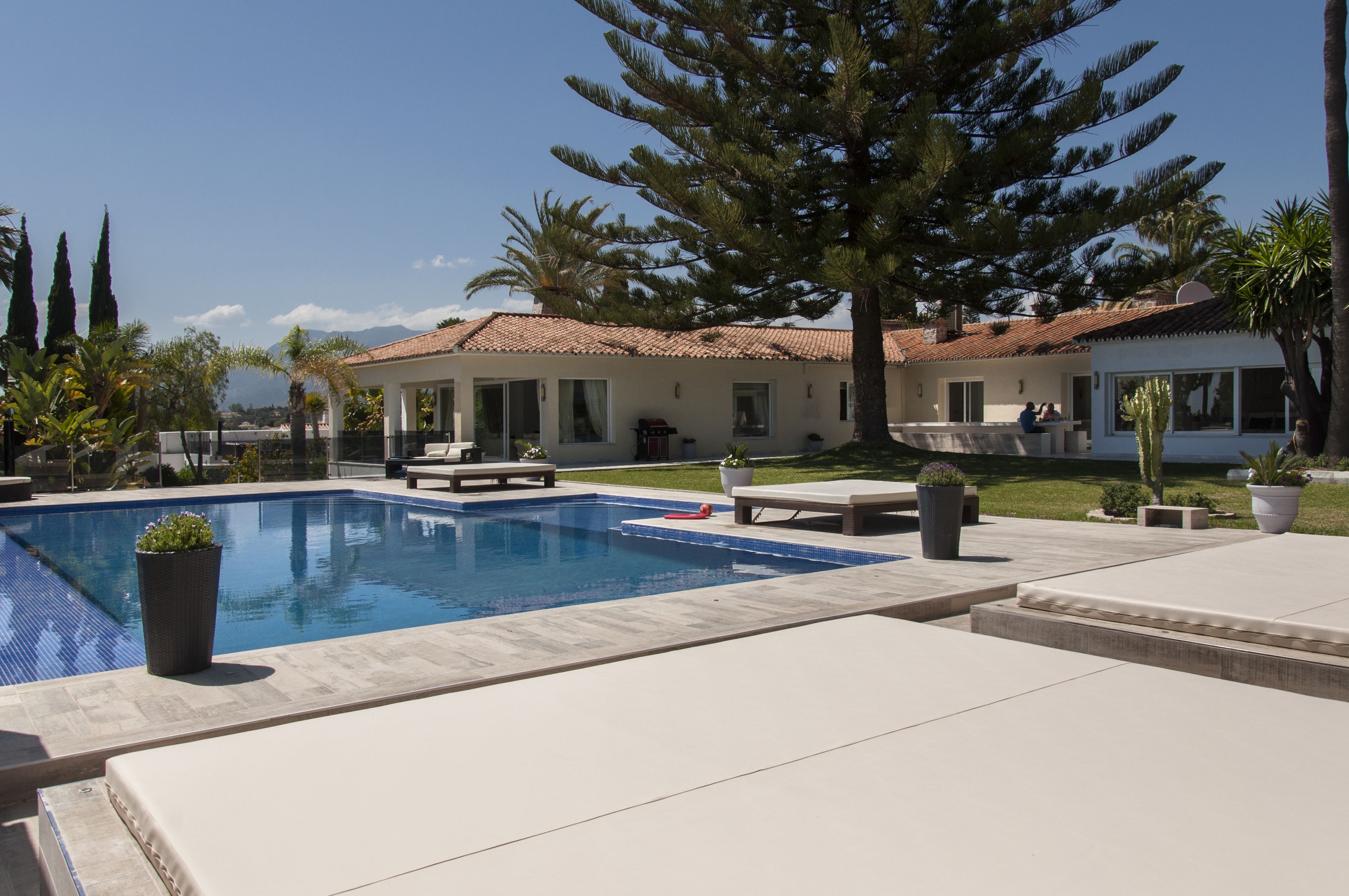 A swimming pool with lounge chairs, a patio area, and a view of mountains in the background.