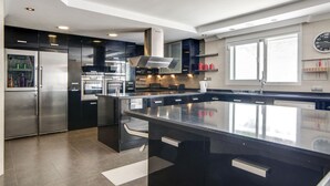 Una cocina moderna con electrodomésticos de acero inoxidable, una isla grande y un ventanal con un reloj.