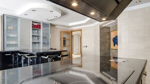 Cocina moderna con isla central, electrodomésticos integrados y un armario con puertas de vidrio.