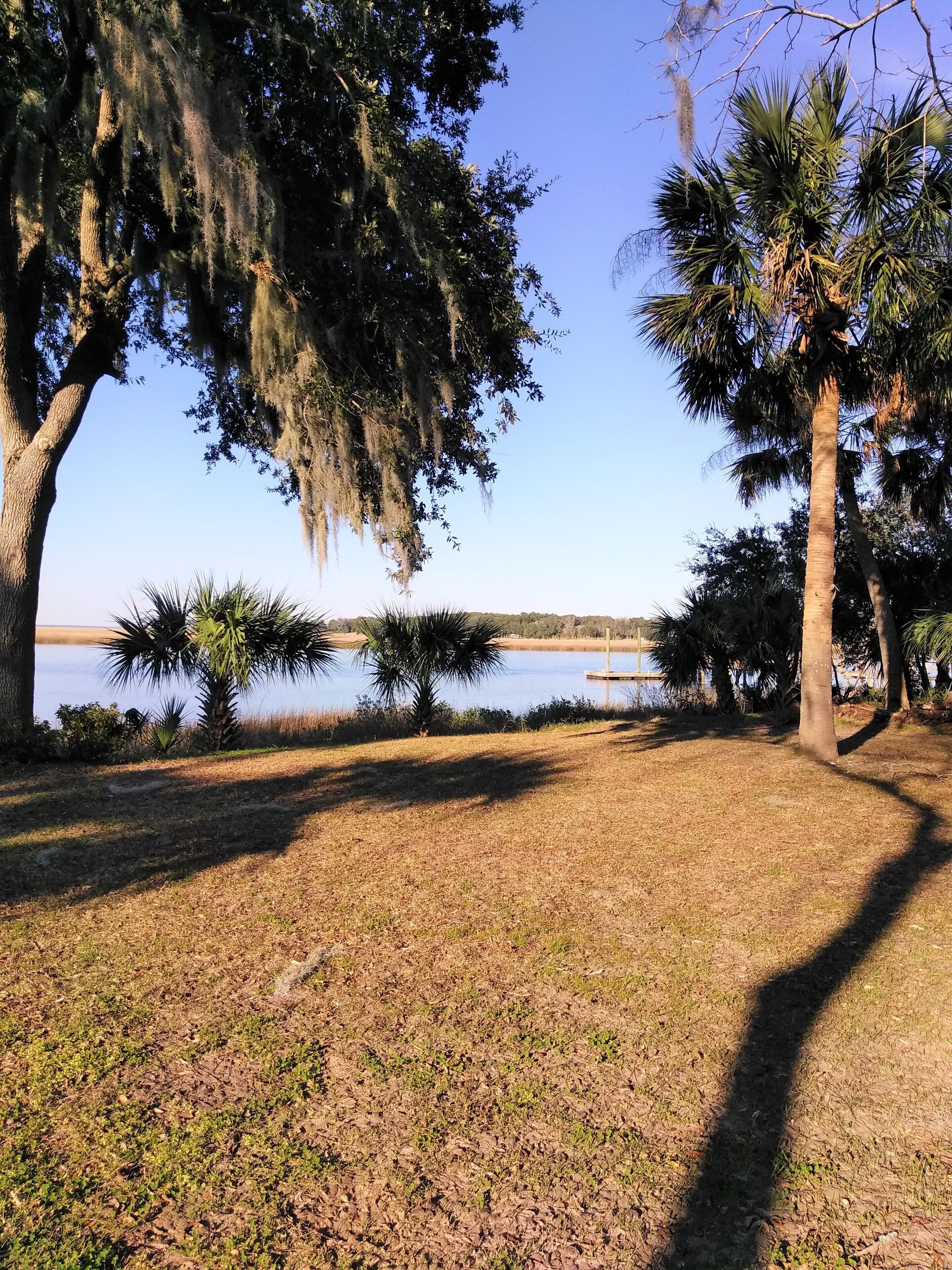 Un parc avec un lac, des arbres et un ciel dégagé.