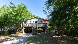 A wooden cabin with a deck, surrounded by trees.
