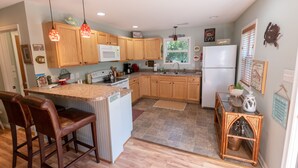 A kitchen with wooden cabinets, a central island with bar stools, a refrigerator, and various kitchen appliances.