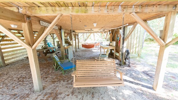 A rustic wooden structure with a bench, a hammock, and a table.