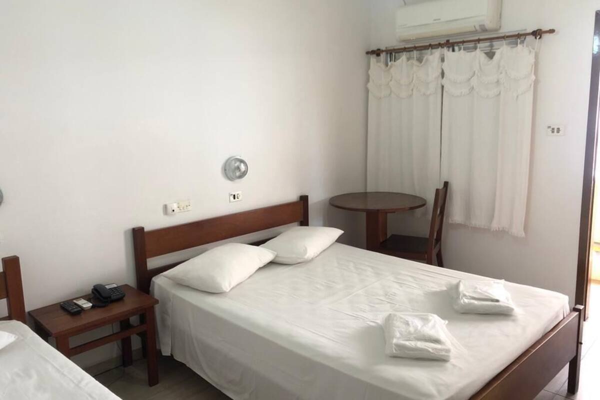 Ein Hotelzimmer mit einem Einzelbett, einem Nachttisch mit Telefon, einem runden Tisch und einem Stuhl.