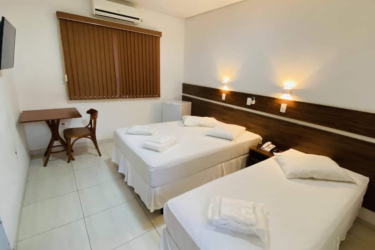 Ein Hotelzimmer mit zwei Betten, einem Schreibtisch, einem Stuhl und einem an der Wand befestigten Telefon.