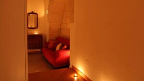 A cozy room with a red sofa, a small table, and a mirror on the wall. - Holiday home L'Alloro with private parking - MATERA (Matera)