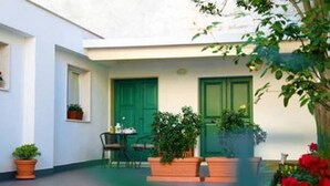 A courtyard with a green door, a table with chairs, and potted plants. - Holiday home L'Alloro with private parking - MATERA (Matera)