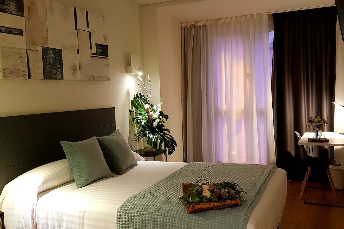 Une chambre à coucher bien rangée, avec un lit, une table de chevet, une lampe et une plante décorative.