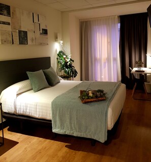 Un dormitorio ordenado con cama, mesita de noche, lámpara y una planta decorativa.