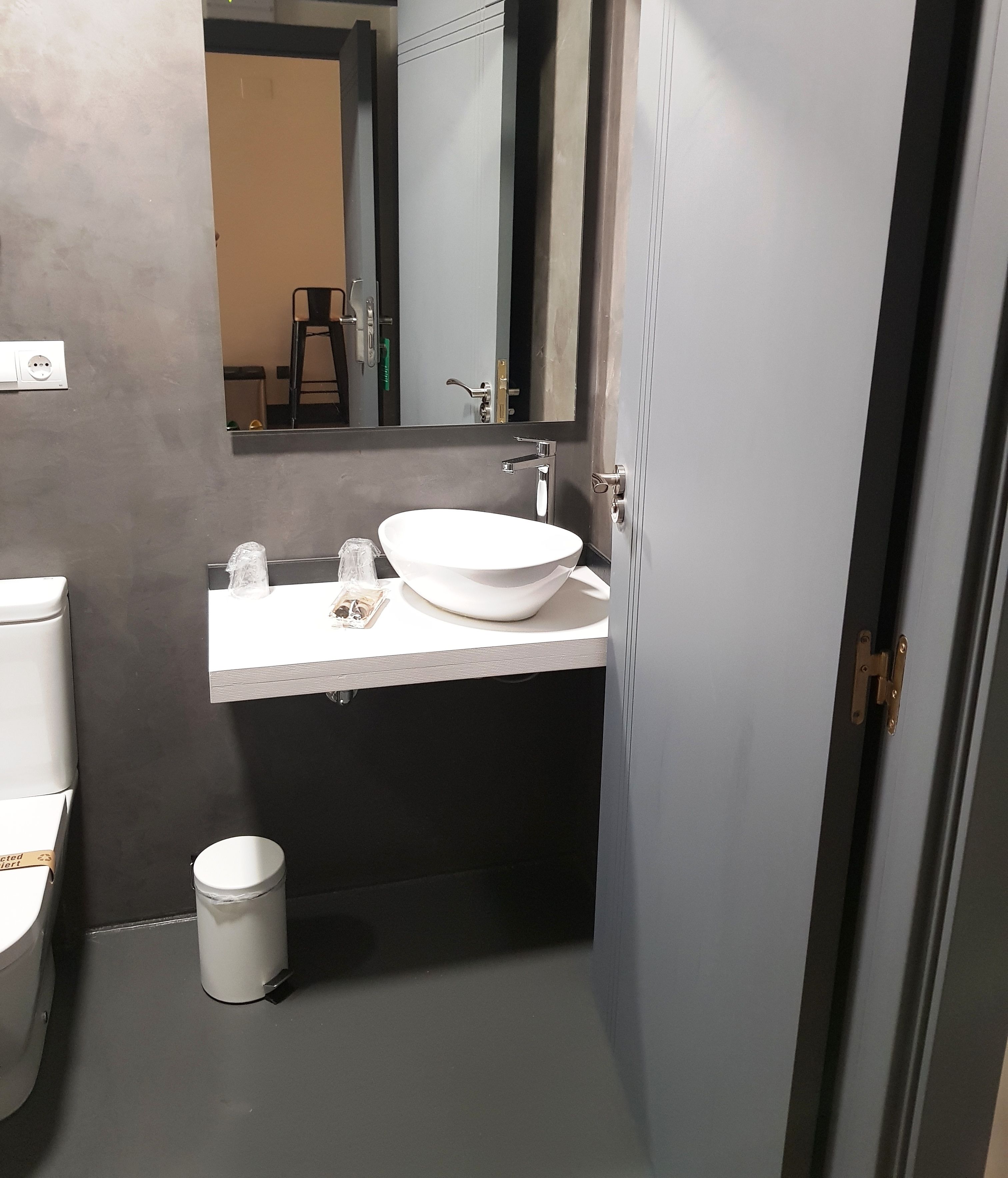 Un baño moderno con un lavamanos blanco, un espejo y un inodoro.