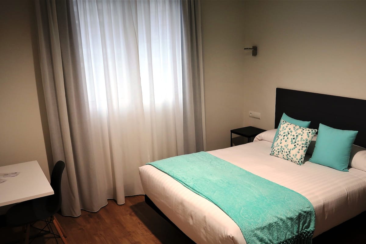 Une chambre d’hôtel bien rangée, avec un lit, un bureau et une chaise.