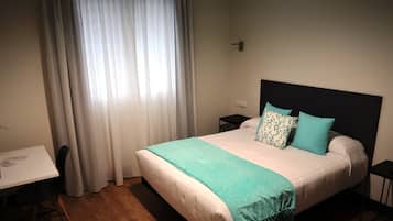 Quarto de hotel bem arrumado com uma cama, uma escrivaninha e uma cadeira.