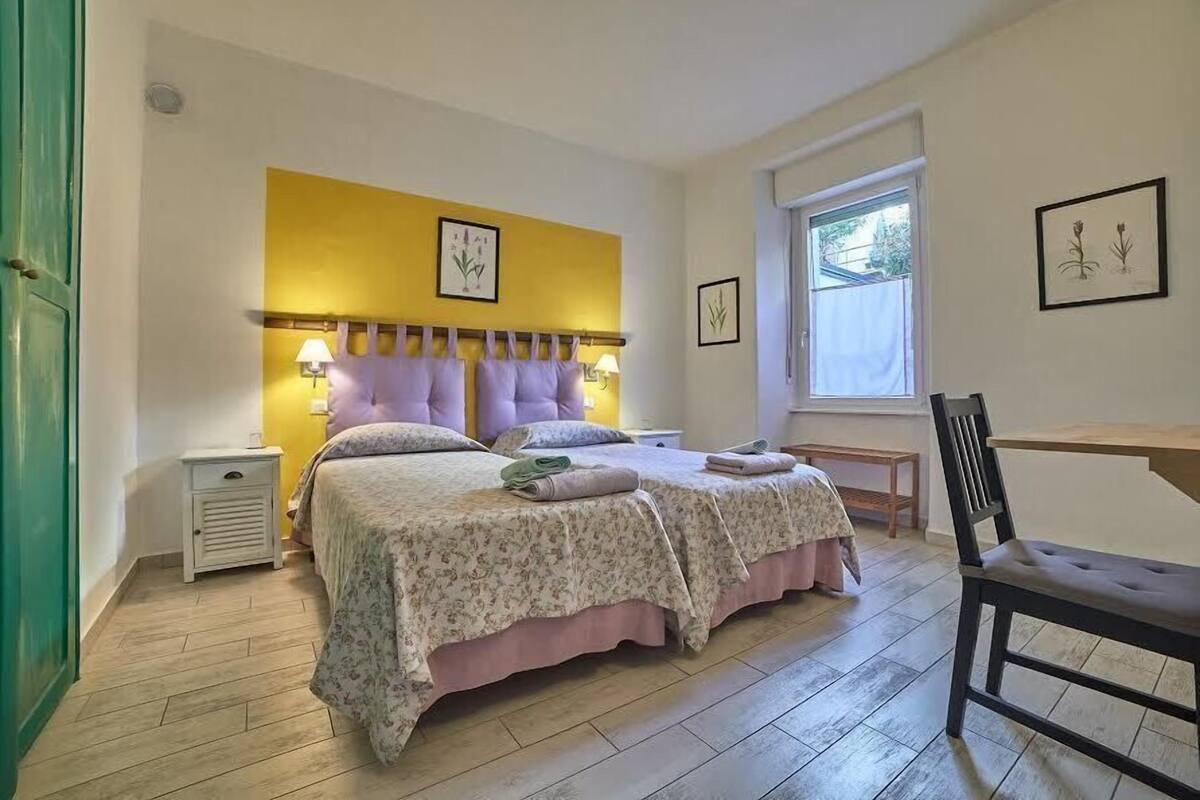 Un dormitorio con cama, mesitas de noche, escritorio y silla.
