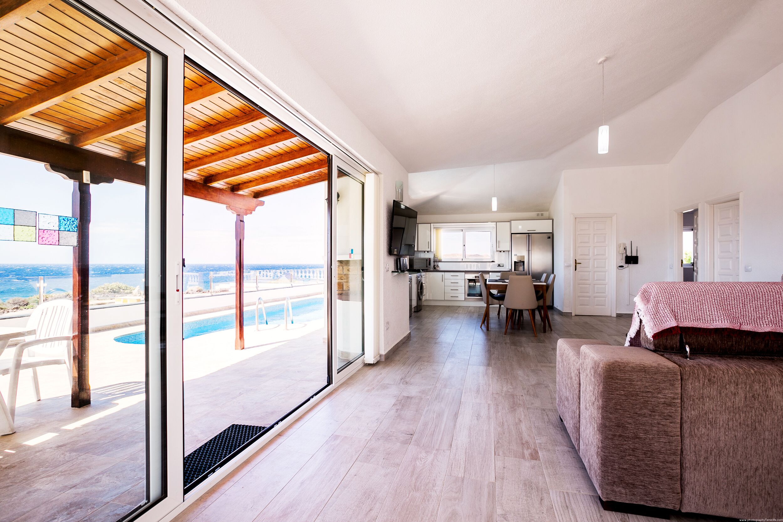 A spacious living area with a large sliding glass door leading to a balcony with a pool view.
