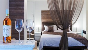 A bedroom with a bed, a canopy, a nightstand, a bottle of Magali wine, and two glasses. - Apartments & Rooms Dujam (Split)