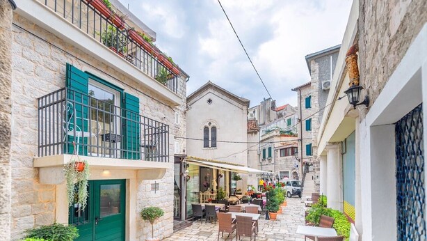 A narrow street with stone buildings, outdoor seating, and a café. - Apartments & Rooms Dujam (Split)