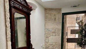 A small, well-lit room with a desk, chair, and a large mirror. There is a small table with a lamp and a potted plant near the door. - Apartments & Rooms Dujam (Split)