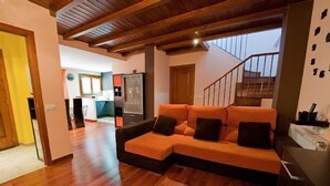 A modern living room with a wooden ceiling, a sectional sofa, and a staircase leading to an upper level. - House Forn for 6 people (Sort)
