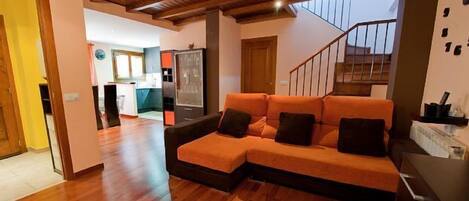 A modern living room with a wooden ceiling, a sectional sofa, and a staircase leading to an upper level.