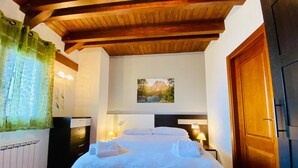 A bedroom with a wooden ceiling, a bed with white bedding, a nightstand with a lamp, and a picture on the wall. - House Forn for 6 people (Sort)
