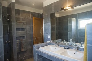 Ein modernes Badezimmer mit zwei Waschbecken, einer Dusche und einem großen Spiegel.