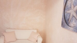 Ein Zimmer mit einem weißen Sofa, einer Wanddekoration mit Seesternen und einer Zeitschrift auf dem Boden.