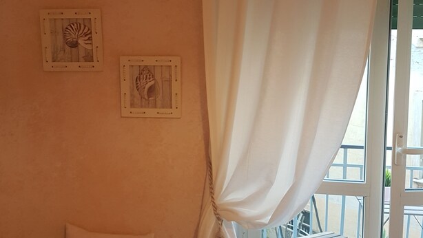 Ein Zimmer mit einer Sitzbank, einem Kissen mit Muschelmotiv und zwei gerahmten Wandbildern.