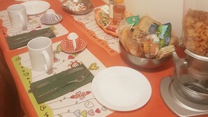 Ein Frühstückstisch mit verschiedenen Speisen, darunter Müsli, Brot und einer Obstschale.