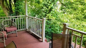 A wooden deck with wicker chairs and a table, surrounded by lush greenery. - Quiet & private in the heart of Peninsula, National Park and on the Towpath (Peninsula)
