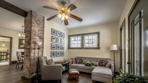 A cozy living room with a brick column, a ceiling fan, a sofa, and a dining area with a table and chairs. - Quiet & private in the heart of Peninsula, National Park and on the Towpath (Peninsula)