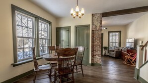 A dining area with a wooden table and chairs, a chandelier, and large windows with a view of trees. - Quiet & private in the heart of Peninsula, National Park and on the Towpath (Peninsula)