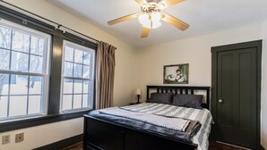 A bedroom with a bed, a ceiling fan, a window with curtains, a door, and a painting on the wall. - Quiet & private in the heart of Peninsula, National Park and on the Towpath (Peninsula)