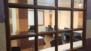 A conference room with a large window, office chairs, and a desk. - The Crescent Suites (Kanayannur)