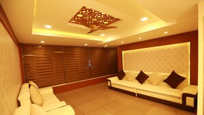 A modern living room with a white sofa, a ceiling fan, and a patterned wall. - The Crescent Suites (Kanayannur)
