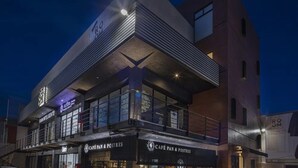 A modern building with a café named "Café Pan & Postres" on the ground floor. - ROOM Hotel & Suites (Puebla)