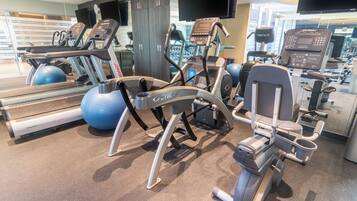 Un gimnasio con máquinas de cardio, máquinas de pesas y pelotas de ejercicio.