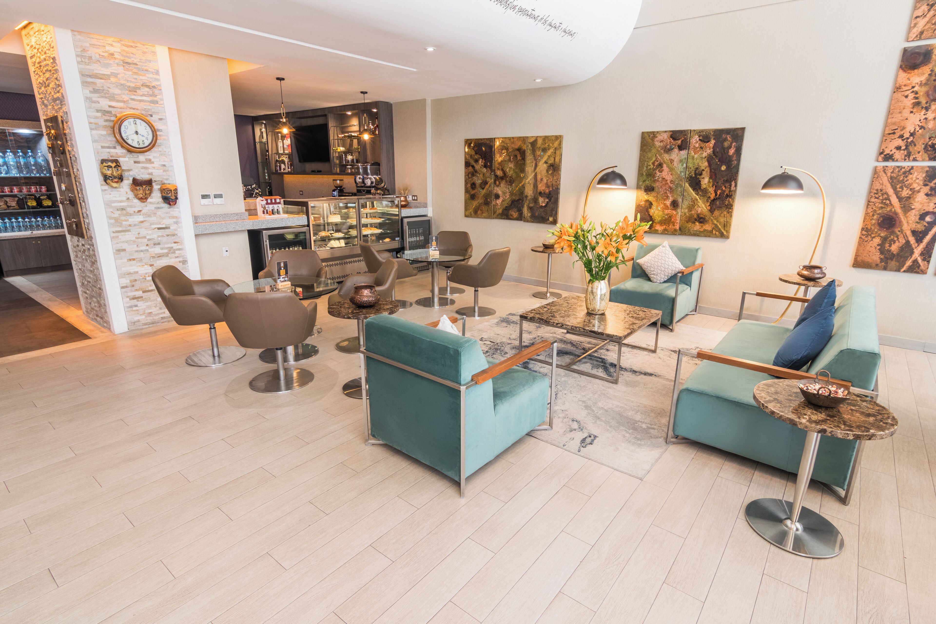 Un hall d’hôtel moderne, doté d’espaces de détente, d’un bar et d’œuvres d’art exposées sur les murs.