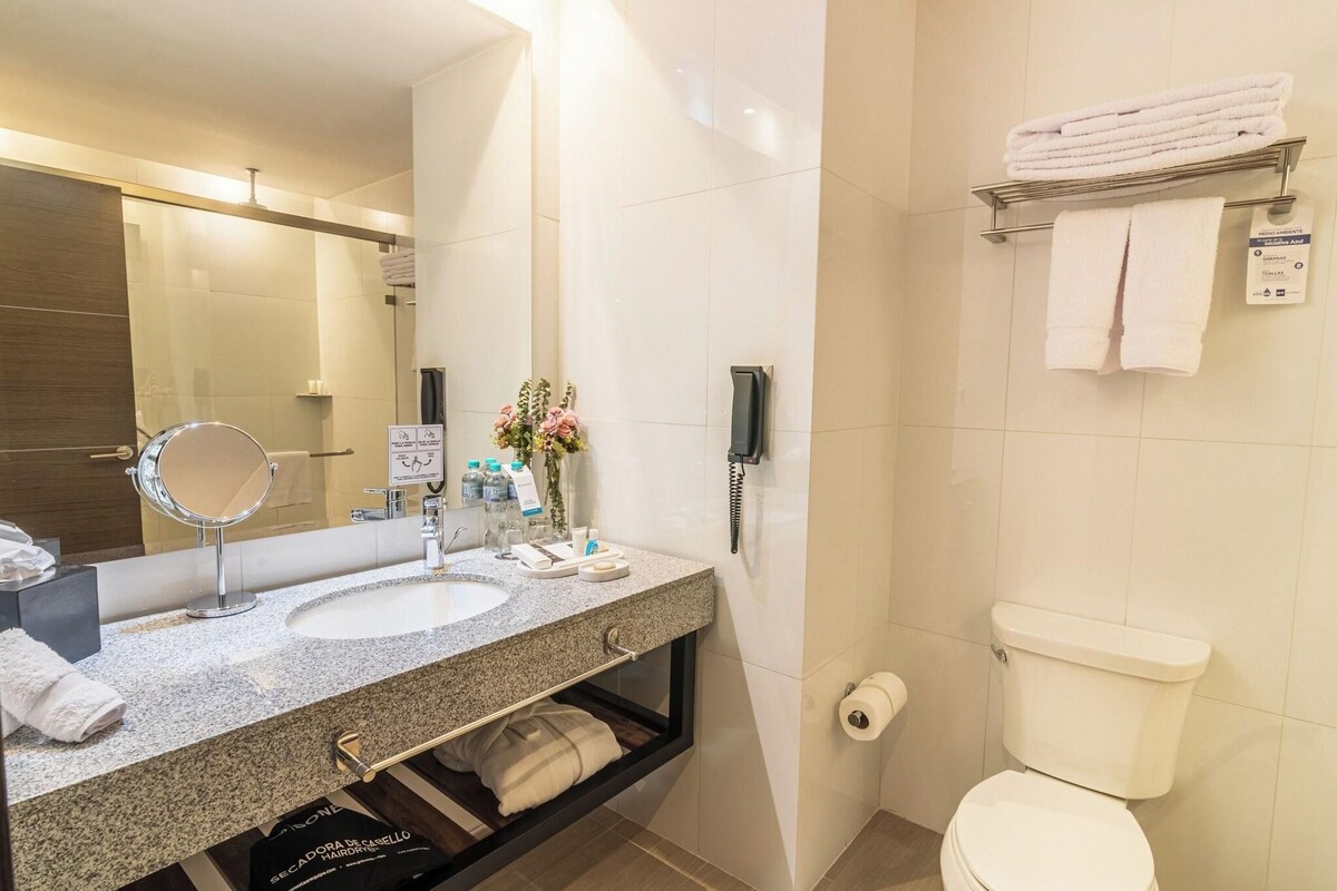 Une salle de bain moderne équipée d’un lavabo, d’un miroir, d’un porte-serviettes, de toilettes et d’un téléphone.