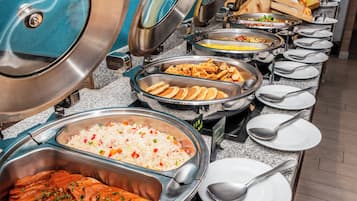 Un bufé con diversas opciones de comida, incluyendo arroz, pollo, gofres y vegetales.