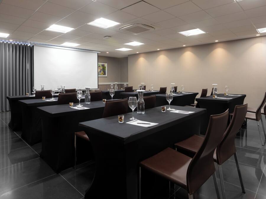 Un salón de conferencias con varias mesas, sillas y vasos.
