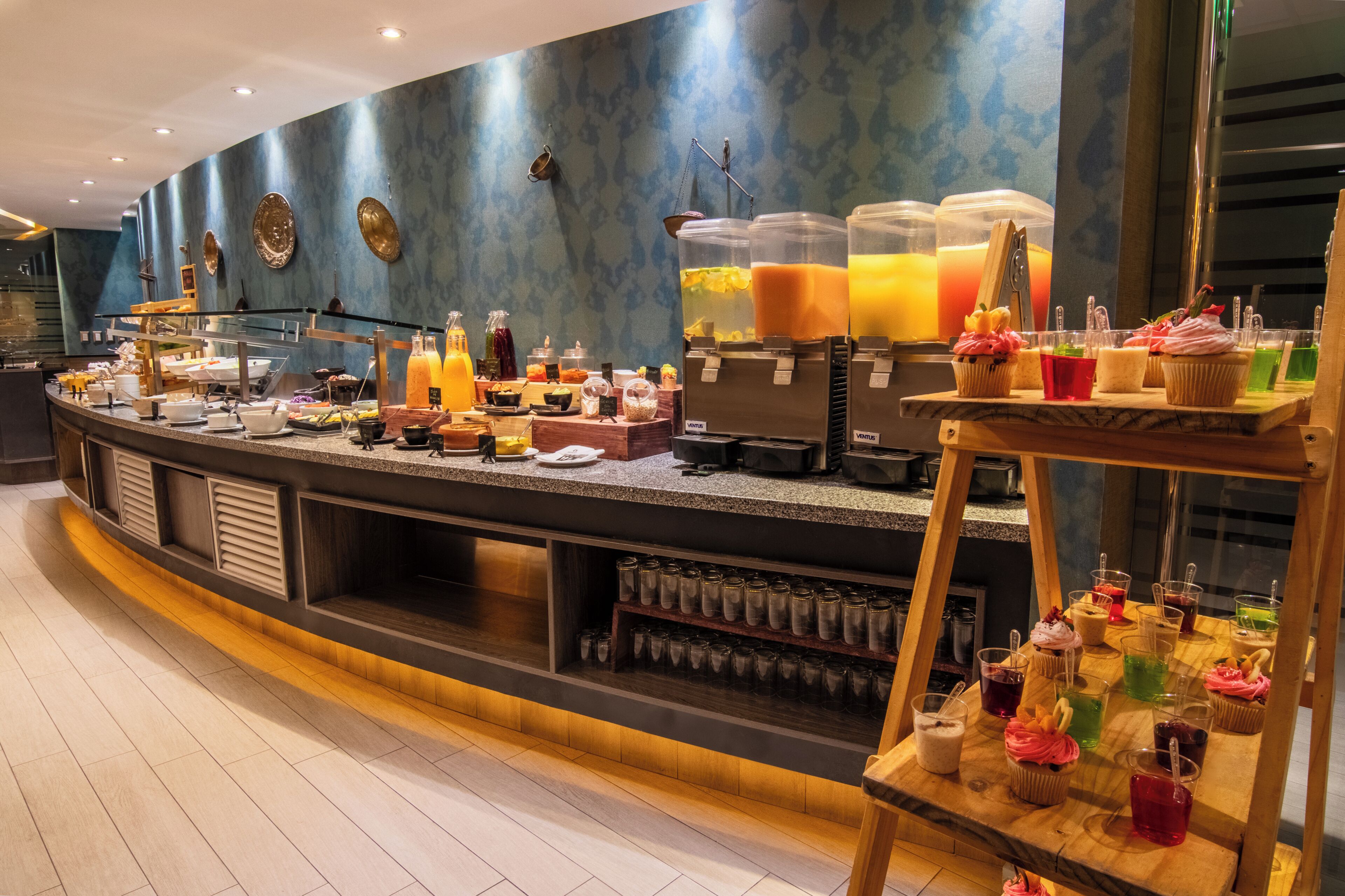A buffet area with various food and drink options, including a selection of juices and a variety of dishes.