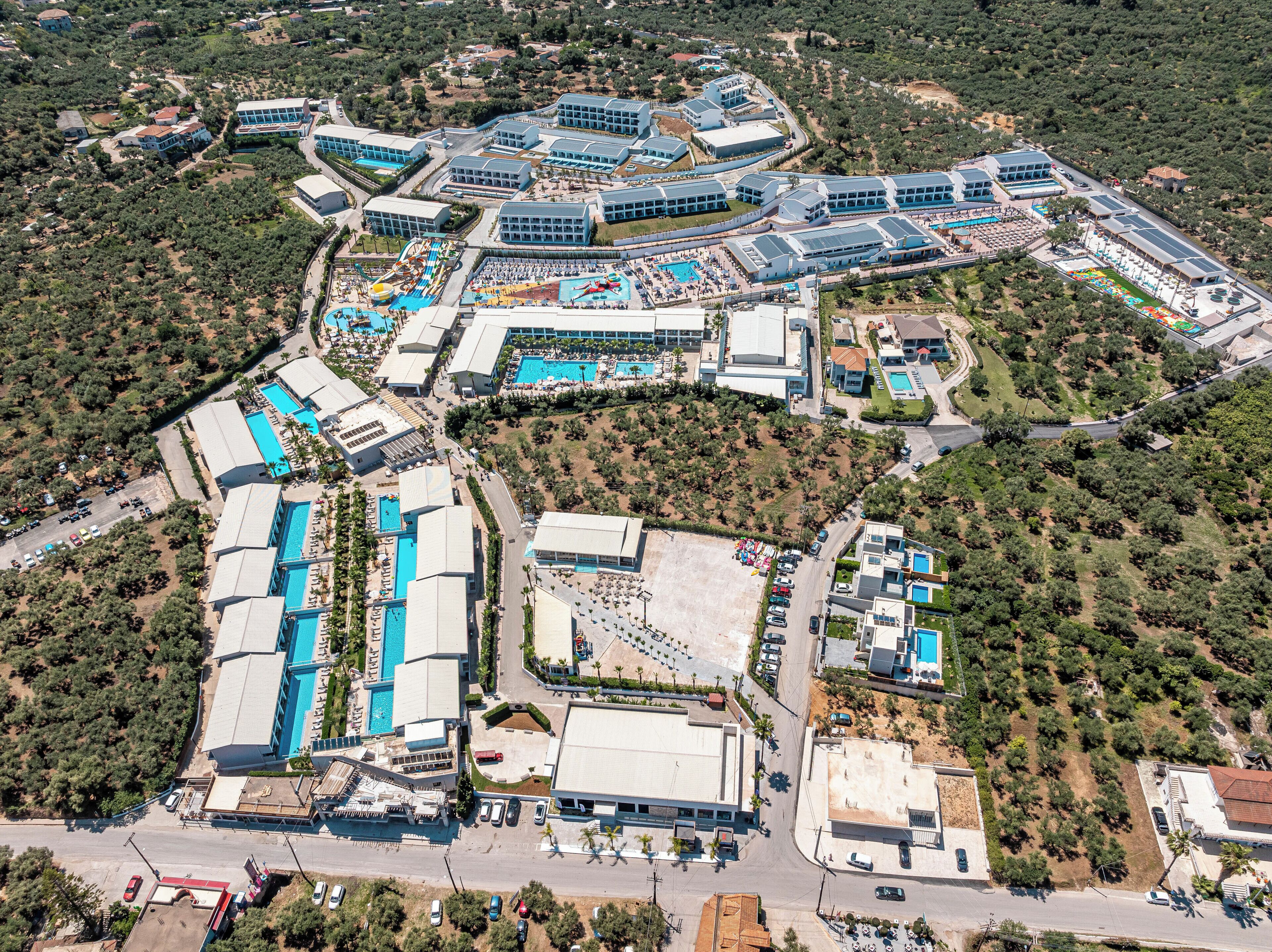 Vista aérea de un complejo turístico con varias edificaciones, piscinas y zonas ajardinadas.