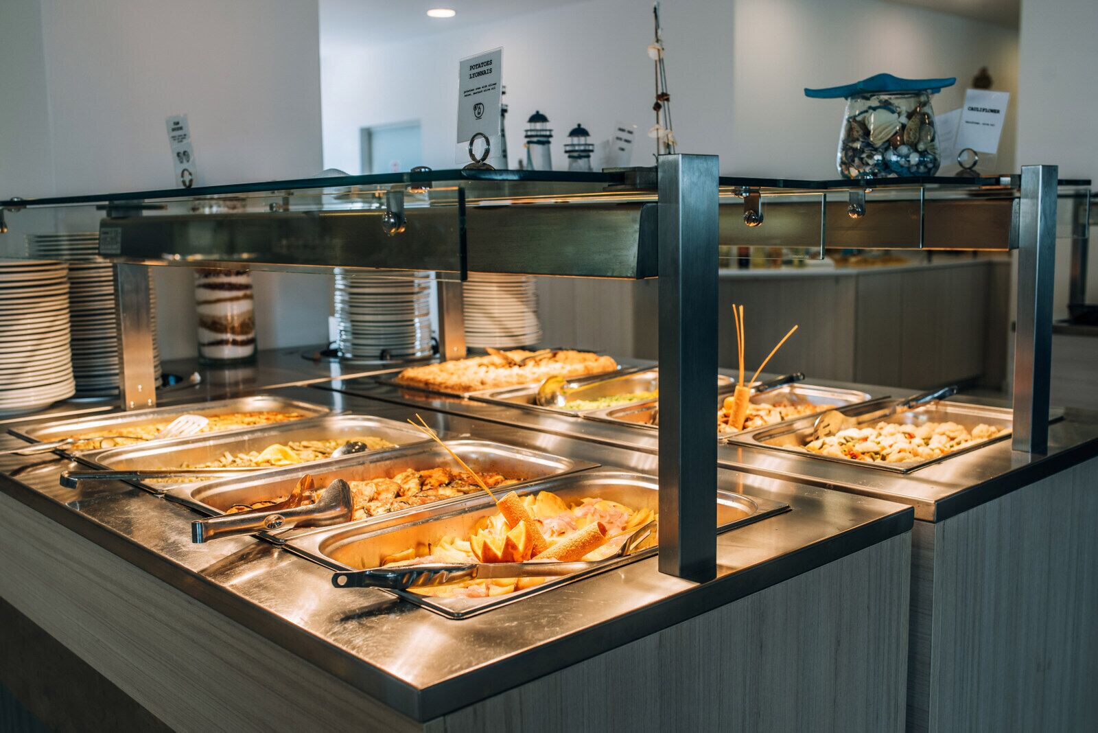 A buffet with multiple food stations, including trays of pasta, salads, and seafood.