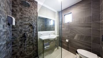 A modern bathroom with a glass-enclosed shower, a white sink, and a toilet.