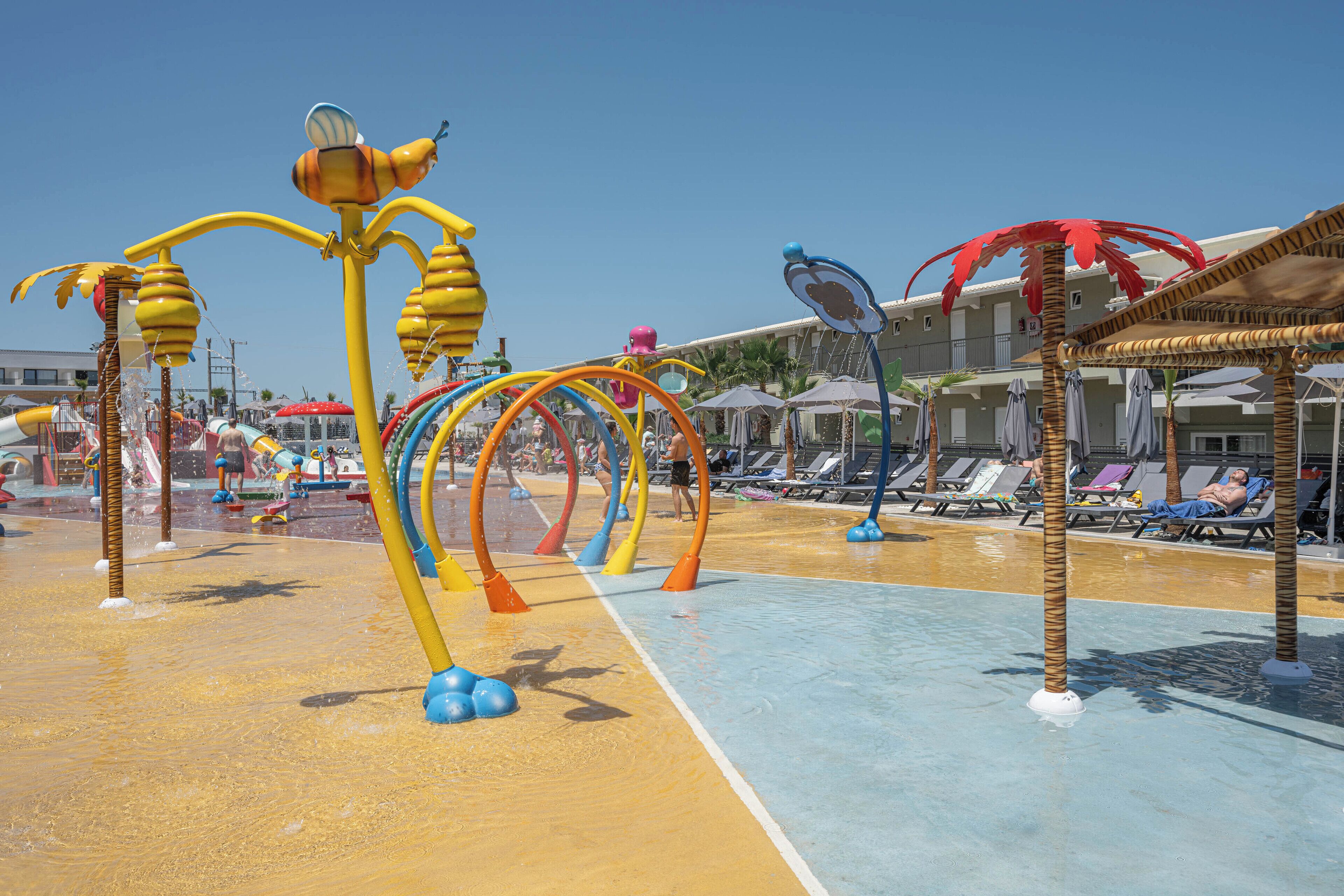 Ein Wasserpark mit bunten Spielgeräten und einem Poolbereich mit Liegestühlen.