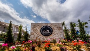A stone wall with a circular emblem that reads "Caretta Paradise Holiday Village." - Caretta Paradise Resort & Waterpark (Zakynthos)