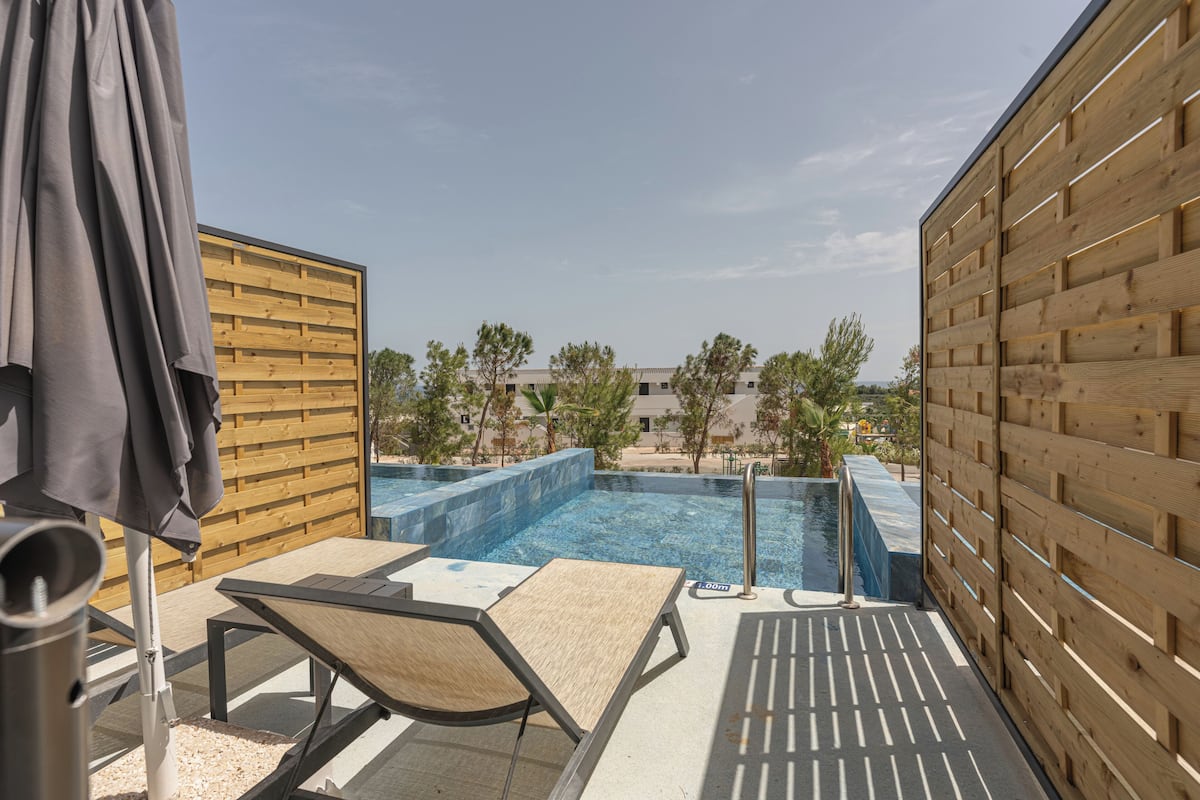 A rooftop pool area with wooden walls, lounge chairs, and a pool table.