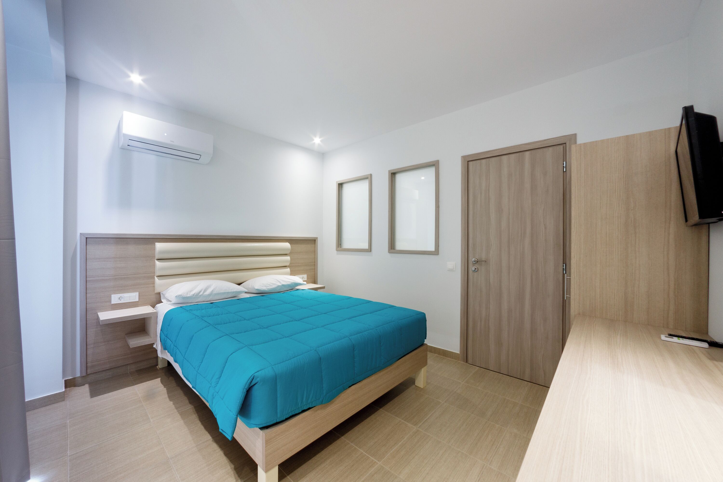 Une chambre à coucher comprenant un lit, des tables de chevet, un climatiseur, une armoire et un téléviseur.
