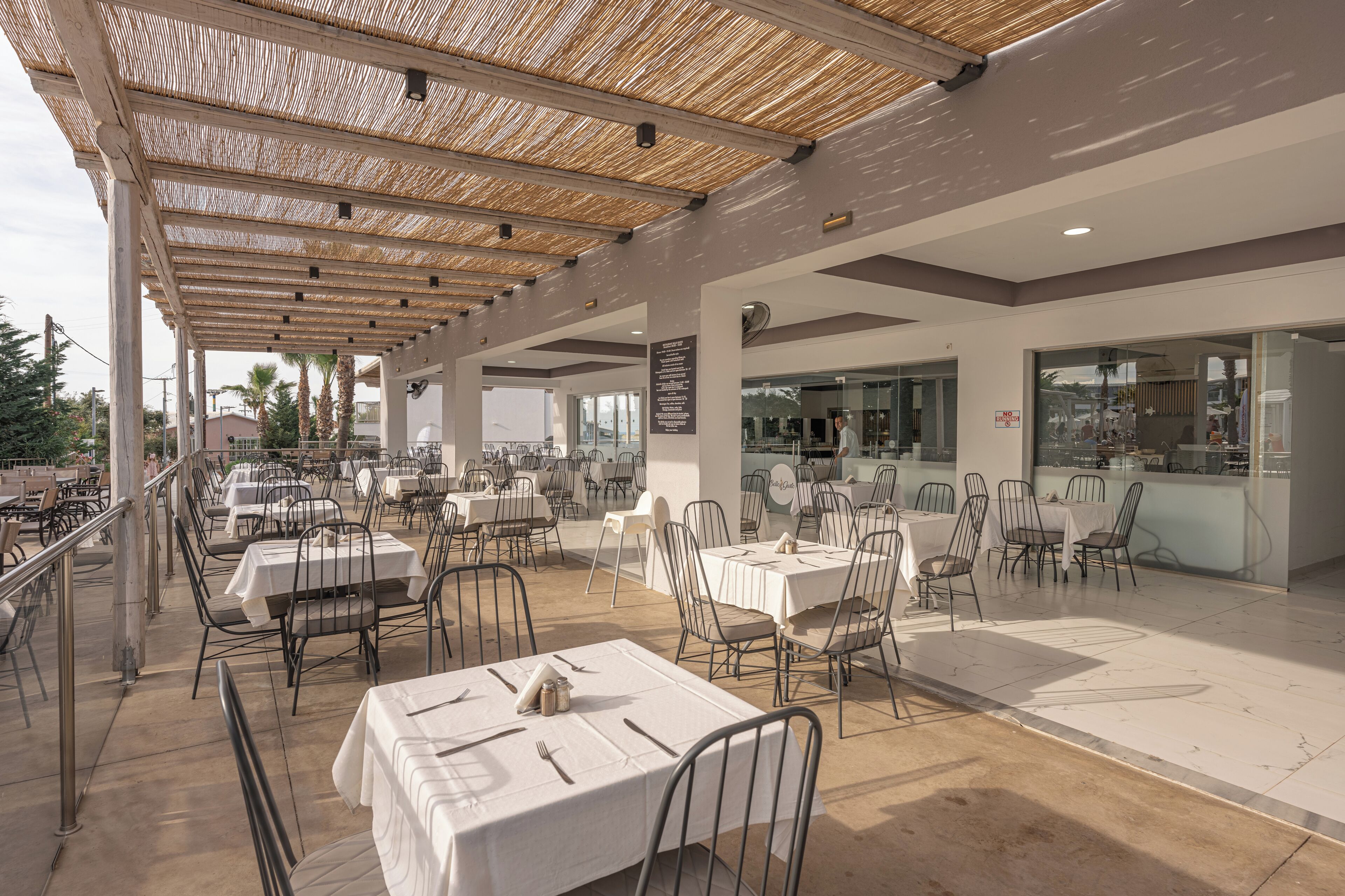 An outdoor dining area with tables and chairs, a covered seating area, and a view of the city.