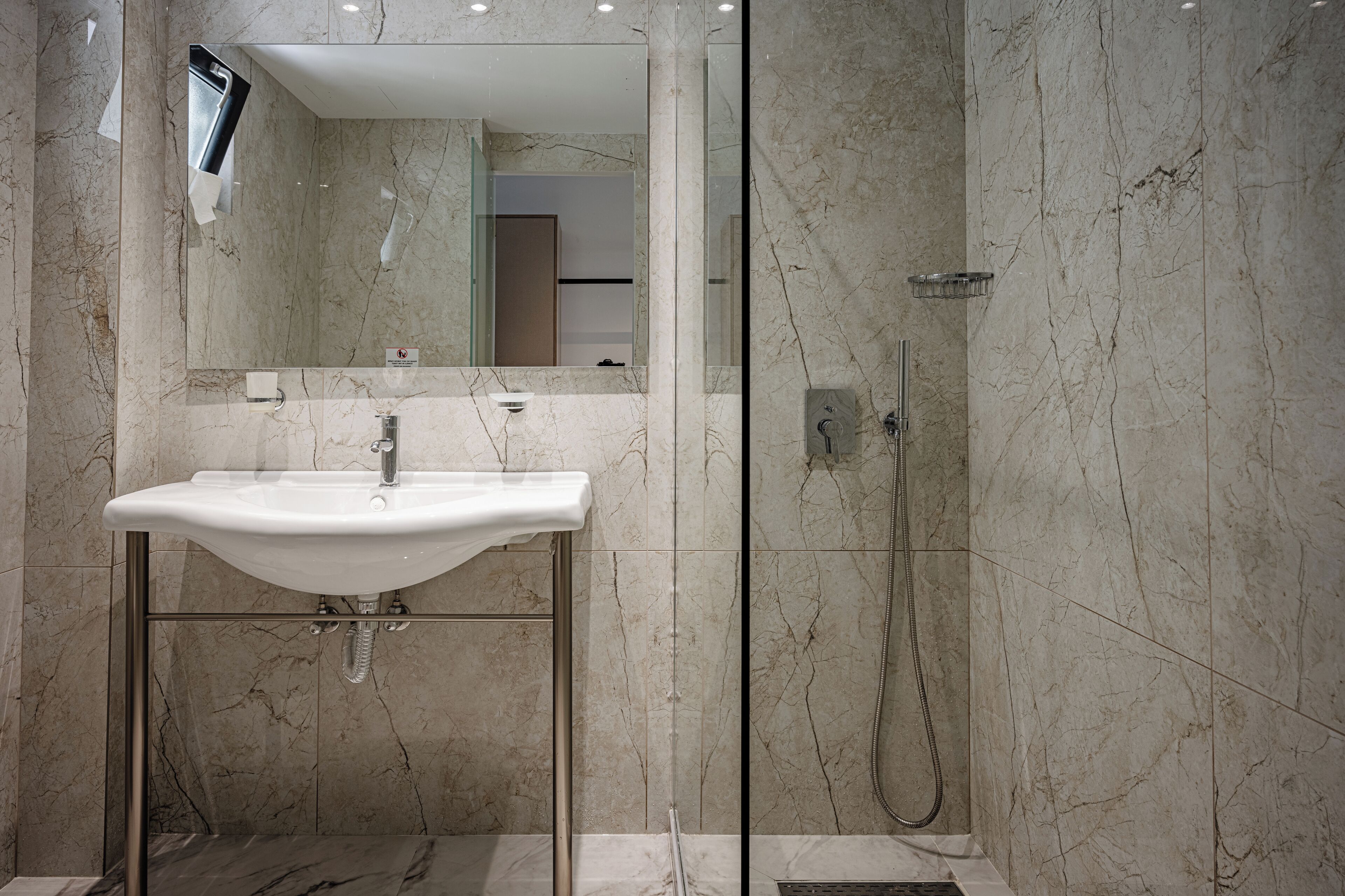 A modern bathroom with a marble sink, glass shower enclosure, and a large mirror.